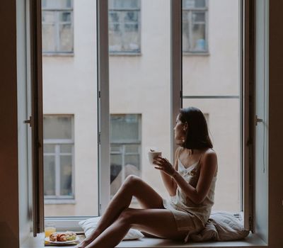 Woman looking out a window after a morning exercise routine.